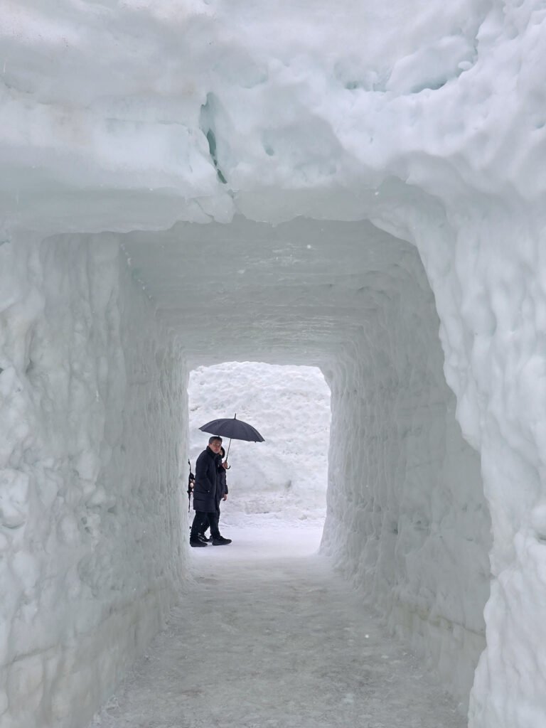 Un tunnel de neige ou une homme passe avec un parapluie